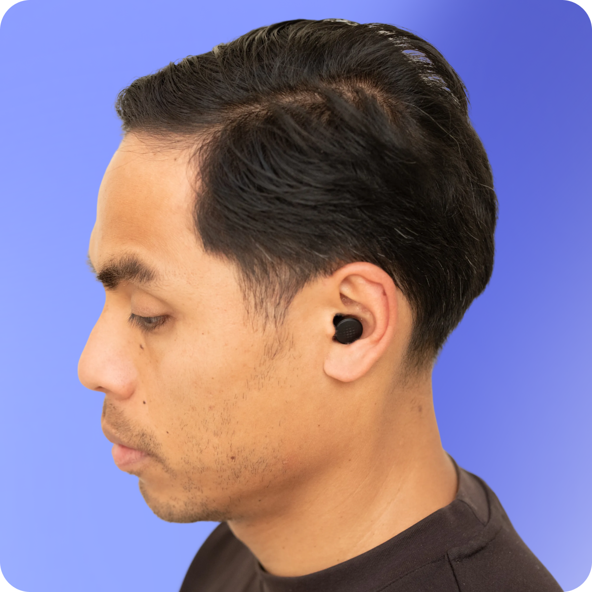 Person wearing a black wireless earbud against a blue background