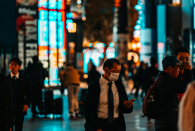 People walking in a city street at night with neon lights and a person wearing a face mask.